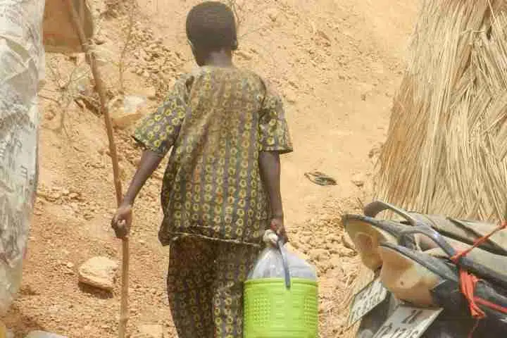 boy walking holding bucket in Burkina Faso