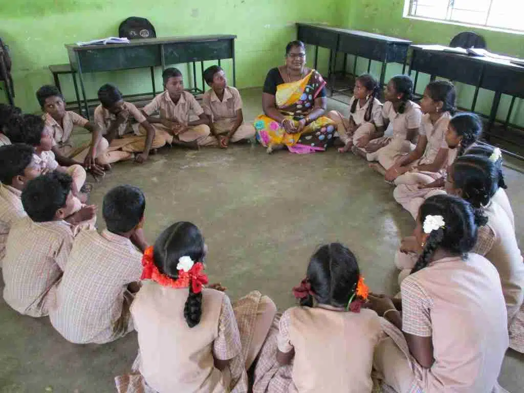 Picture of students and teacher sitting in a circle