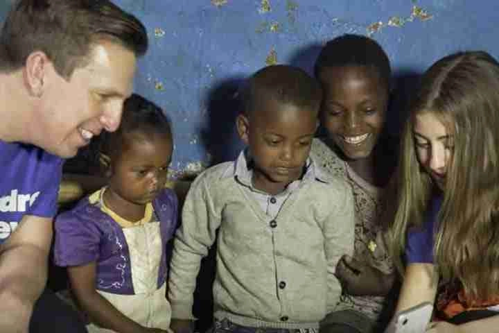 Kids looking in the phone with Children Believe Volunteers