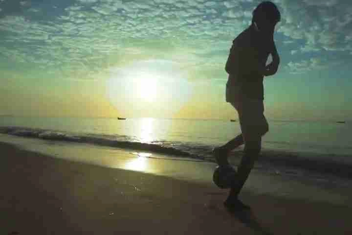 Boy playing football on the beach