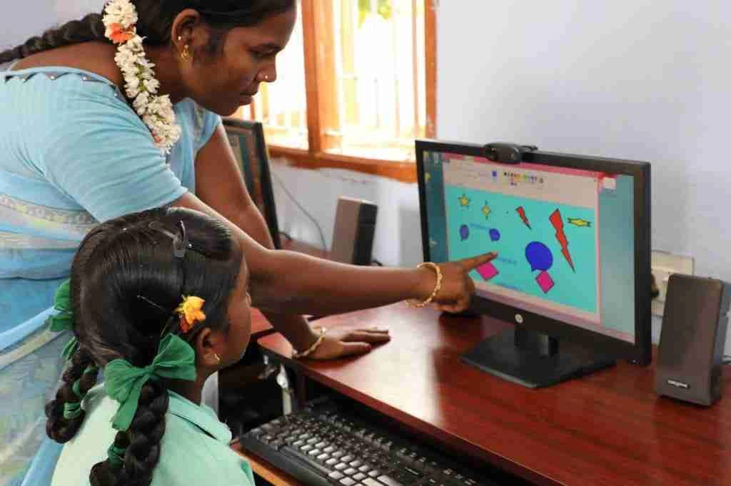 Teacher showing how to use computer to a student